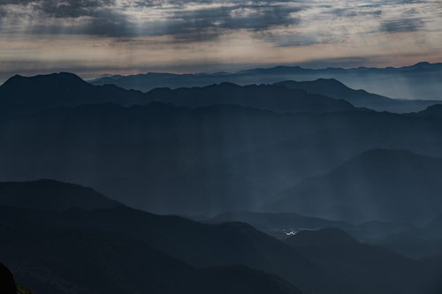 山間部の稜線から差し込む光と連なる山々の眺望