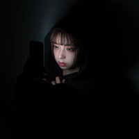 深夜にスマートフォンのタイムラインを見つめる女性の写真