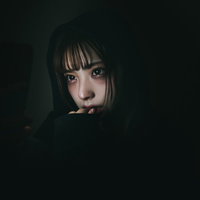 暗がりでスマートフォンを見つめるスマホ依存女子の写真