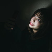他人の不幸は蜜の味ィィ　暗がりでスマートフォンを見つめる女性の写真