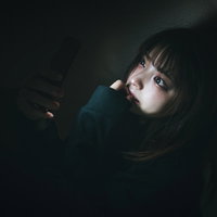 夜な夜なTikTokで時間が溶ける、スマホに没頭する女性の写真