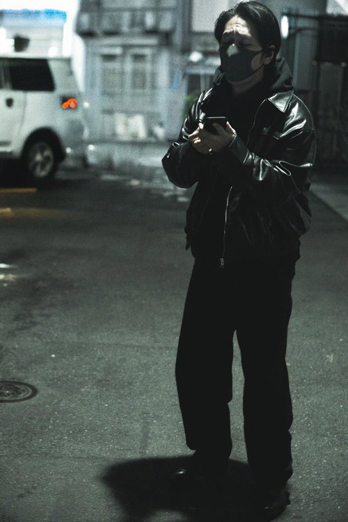 夜の街を夜回りする怪しい男性がスマートフォンを操作