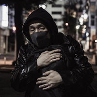 深夜の都会で荷物の受け渡しを待つ不審な男性の写真