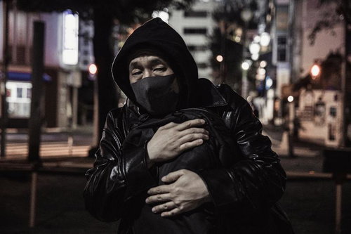 深夜の都会で荷物の受け渡しを待つ不審な男性