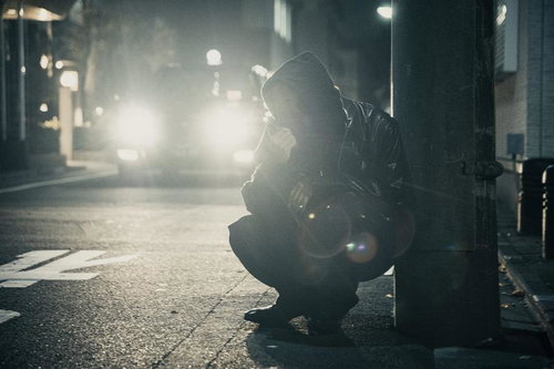 タクシーのライトに照らされる闇バイト中の怪しい男性