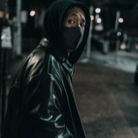 夜間の路上でフードを被った不審な男性の後ろ姿の写真