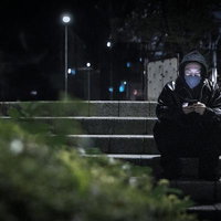 深夜の人通りのない場所で指示を待つ黒ずくめ姿の男性の写真