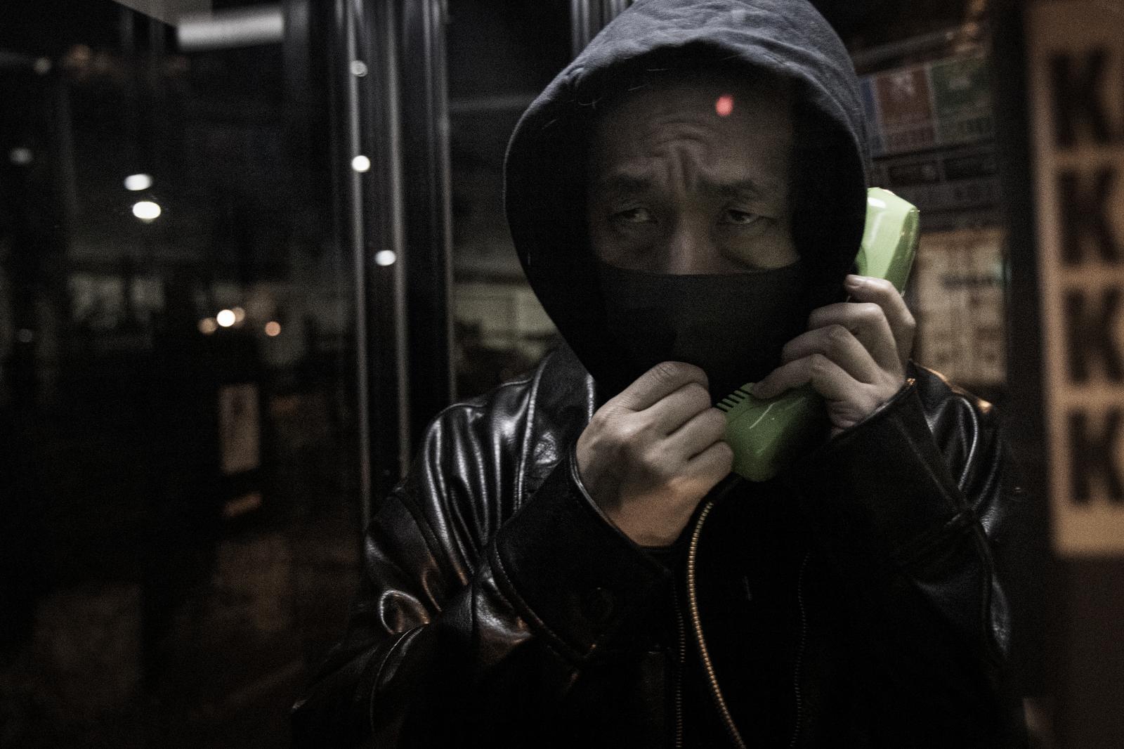 電話ボックスで闇バイトの勧誘を受ける夜間の男性［モデル：大川竜弥］