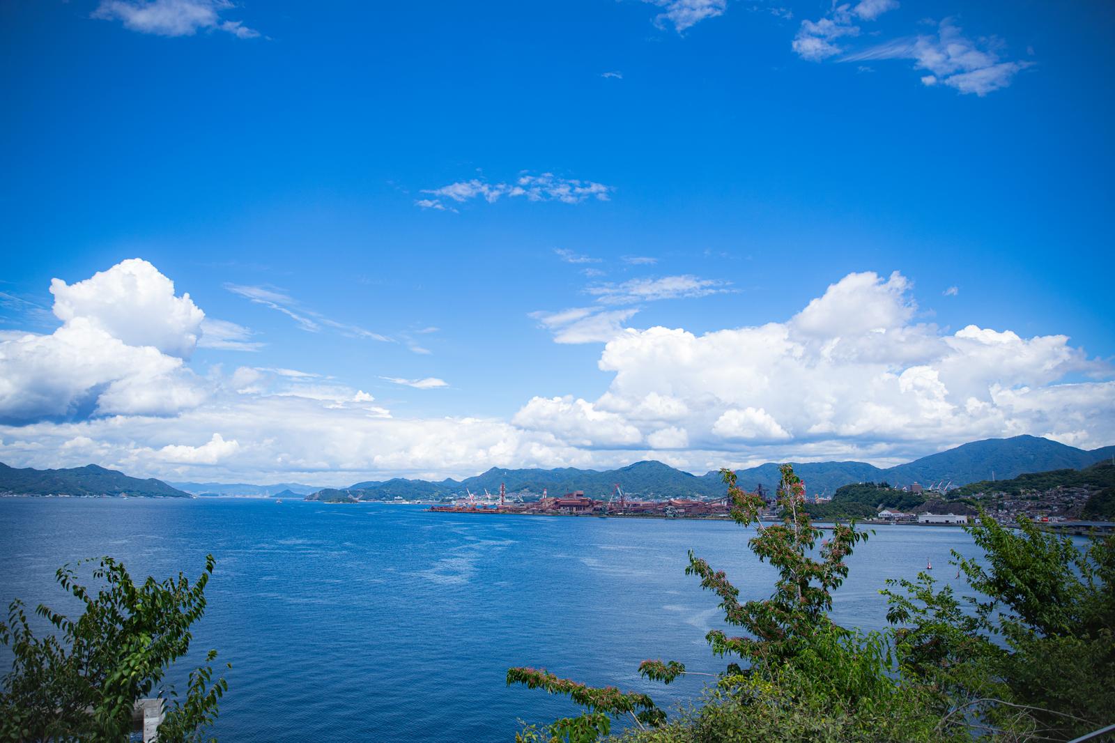 広島の工場地帯と海峡を望む眺望、青空に白い雲が浮かぶ風景