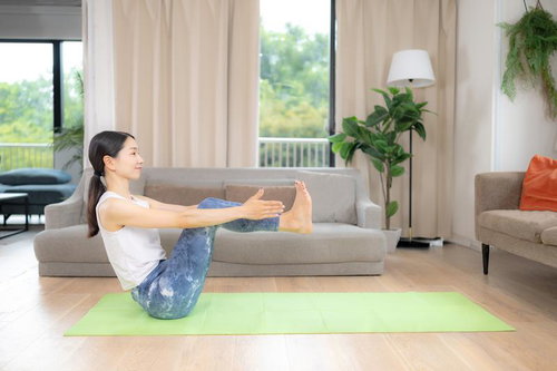 ヨガマットの上で舟のポーズをする女性