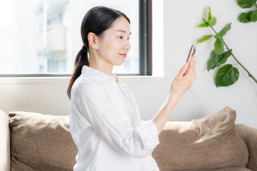 白いシャツを着た女性がスマートフォンを正しい姿勢で操作