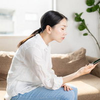 ソファでスマートフォンを見る女性の写真