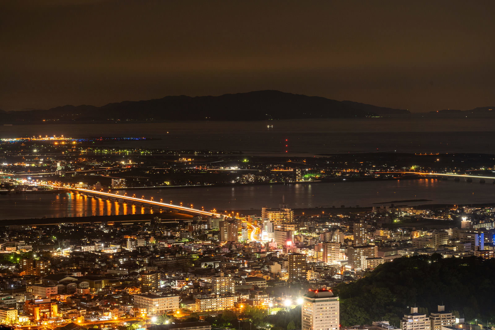 山々に囲まれた徳島県の市街地夜景、橋と建物の明かりが美しく輝く