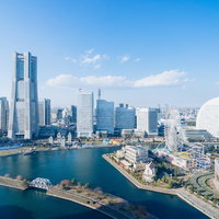 青空に映るみなとみらいランドマークタワーとコスモワールドの景観の写真
