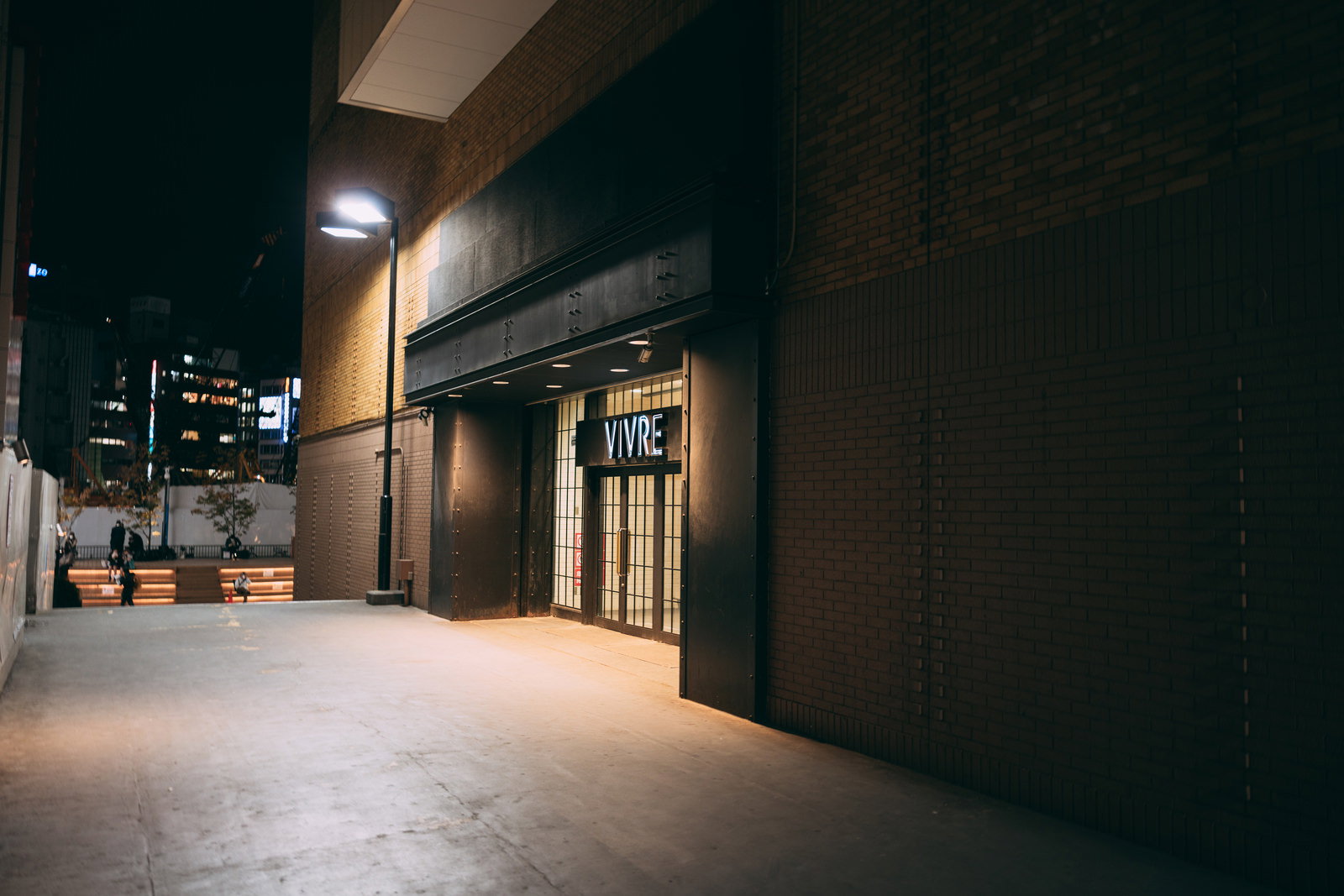 夜のVIVRE横の通路と広場、暖かい照明が印象的な商業施設