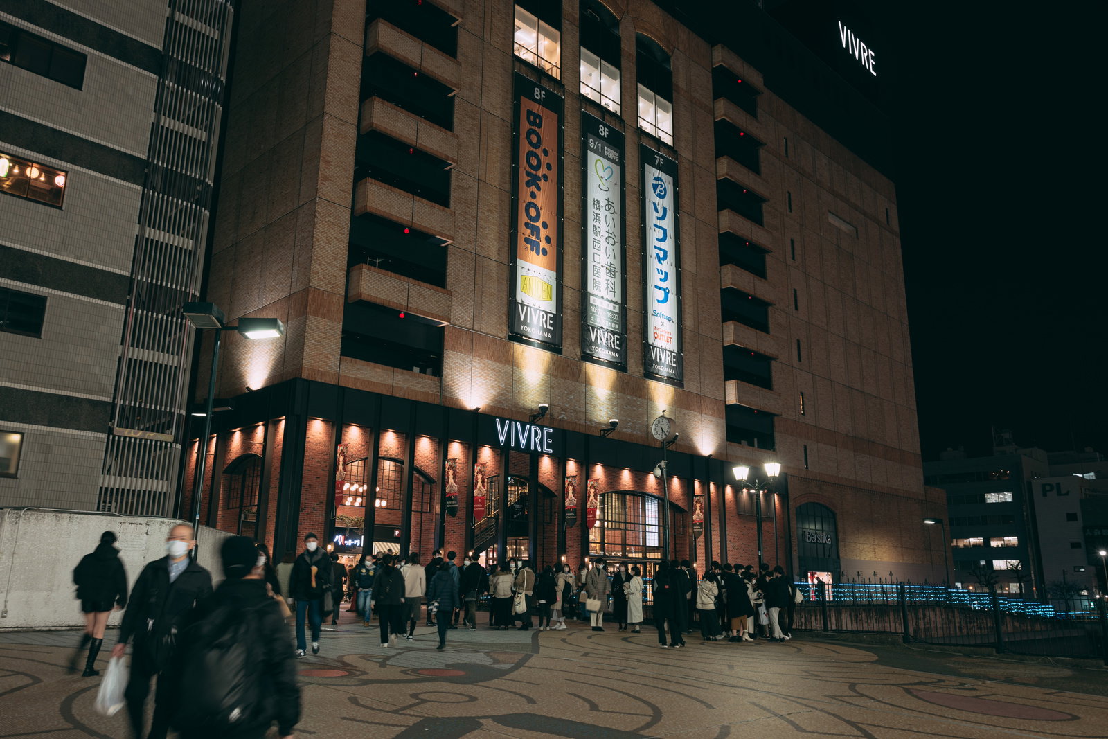 夜の横浜VIVREビル前に集まる人混みと illuminated な商業施設