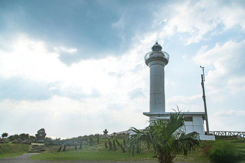 日本最西端与那国島の白い円柱型灯台と南国植物