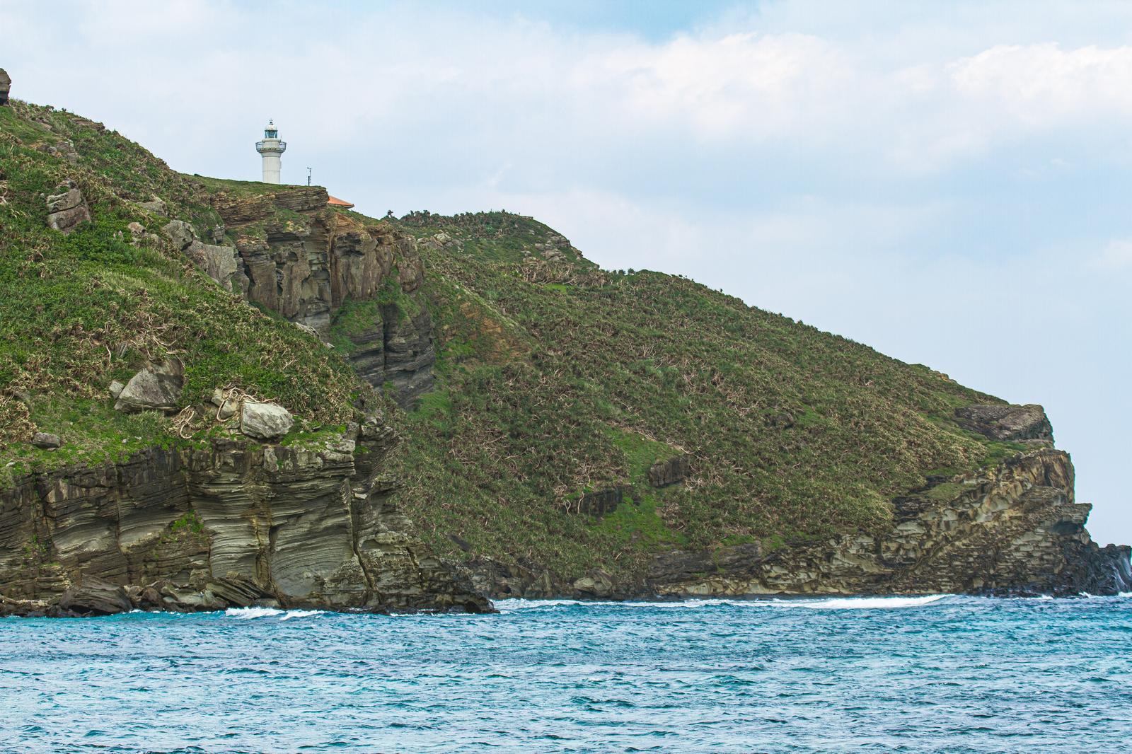 White lighthouse on the coast of Yonaguni Island, with green cliffs and the deep blue ocean