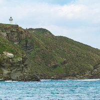 白い灯台が立つ断崖絶壁に囲まれた与那国島の美しい海岸風景の写真