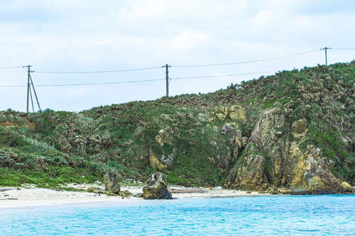 岩場と白砂浜が広がる与那国島の海岸風景と送電線