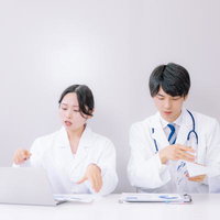 デスクでカルテを確認しながら説明する医師たちの写真