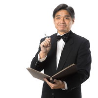 笑顔で言付けをメモするジェントルなウェイターの写真