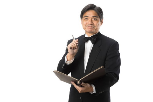 笑顔で言付けをメモするジェントルなウェイター