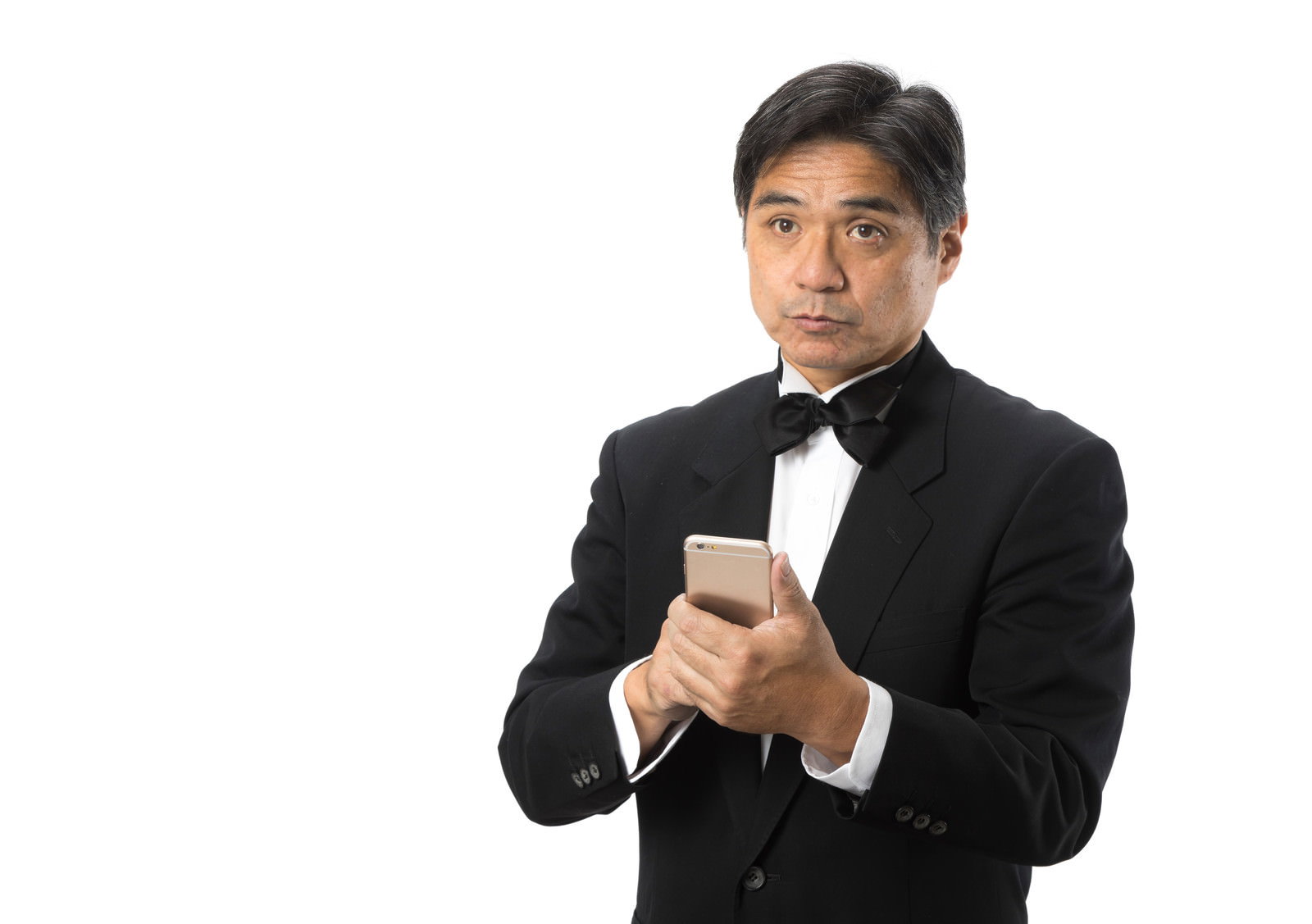 黒いスーツと蝶ネクタイを着用した執事がスマートフォンを操作している［モデル：よたか］