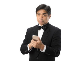 スマートフォンで翻訳しながら対話する執事男性の写真
