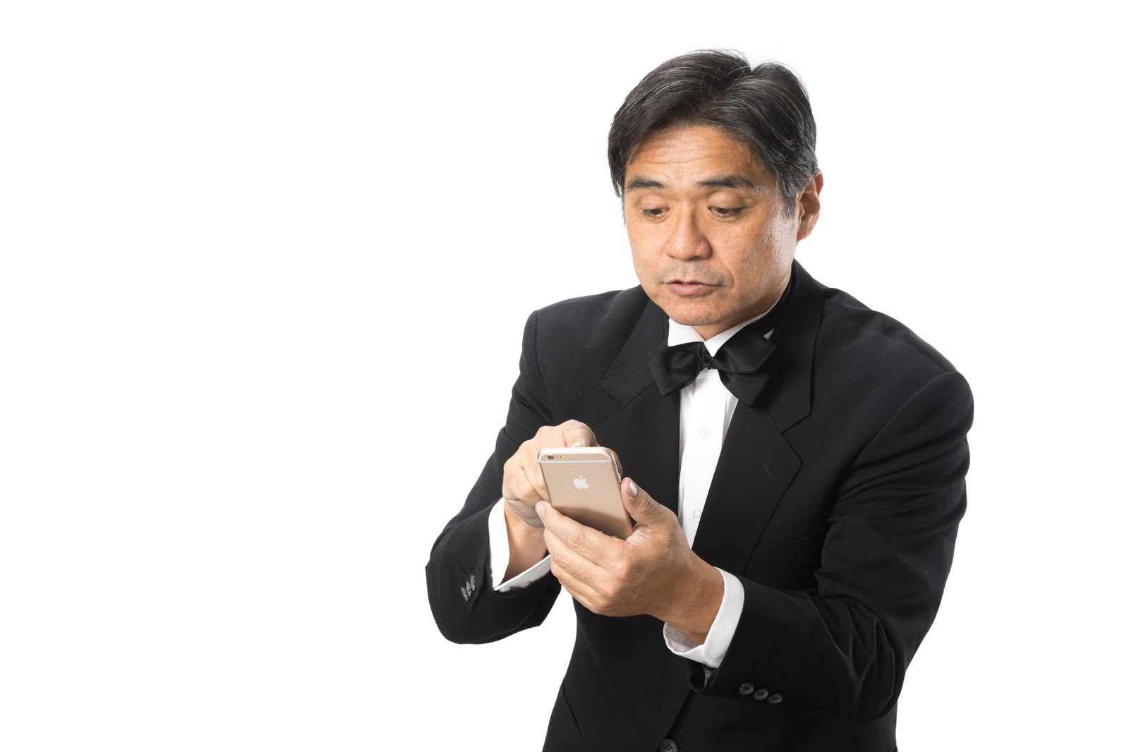 黒いスーツと蝶ネクタイを着た支配人がスマートフォンを見て困った表情をしている［モデル：よたか］