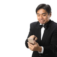 苦手なスマートフォンを使う中年執事の操作風景の写真