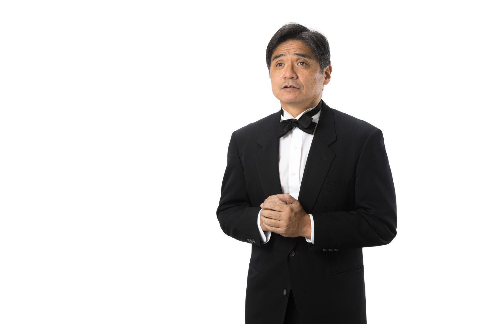 黒いタキシードと蝶ネクタイを着た中年男性が心配そうな表情で見つめている［モデル：よたか］