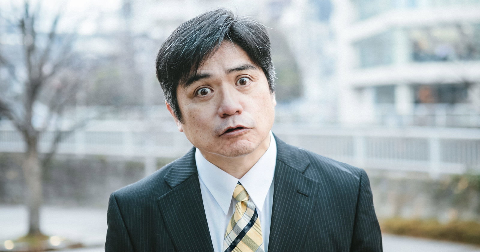 黒いスーツを着た中間管理職の男性が怒りの表情を見せている［モデル：よたか］