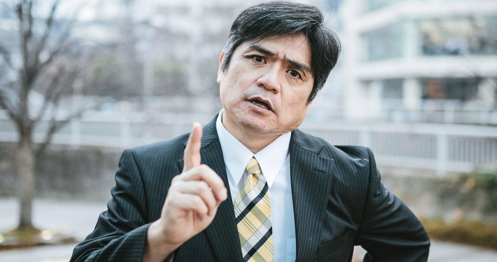 スーツ姿の男性会社員が怒った表情で指を立てているポーズ［モデル：よたか］