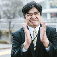 拍手喝采を送るスーツ姿の男性部長の笑顔と桜の写真