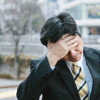 頭を抱えて悩む中年上司のビジネスパーソンの写真