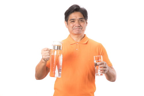 ミネラルウォーターのグラスを持つ笑顔の中年男性