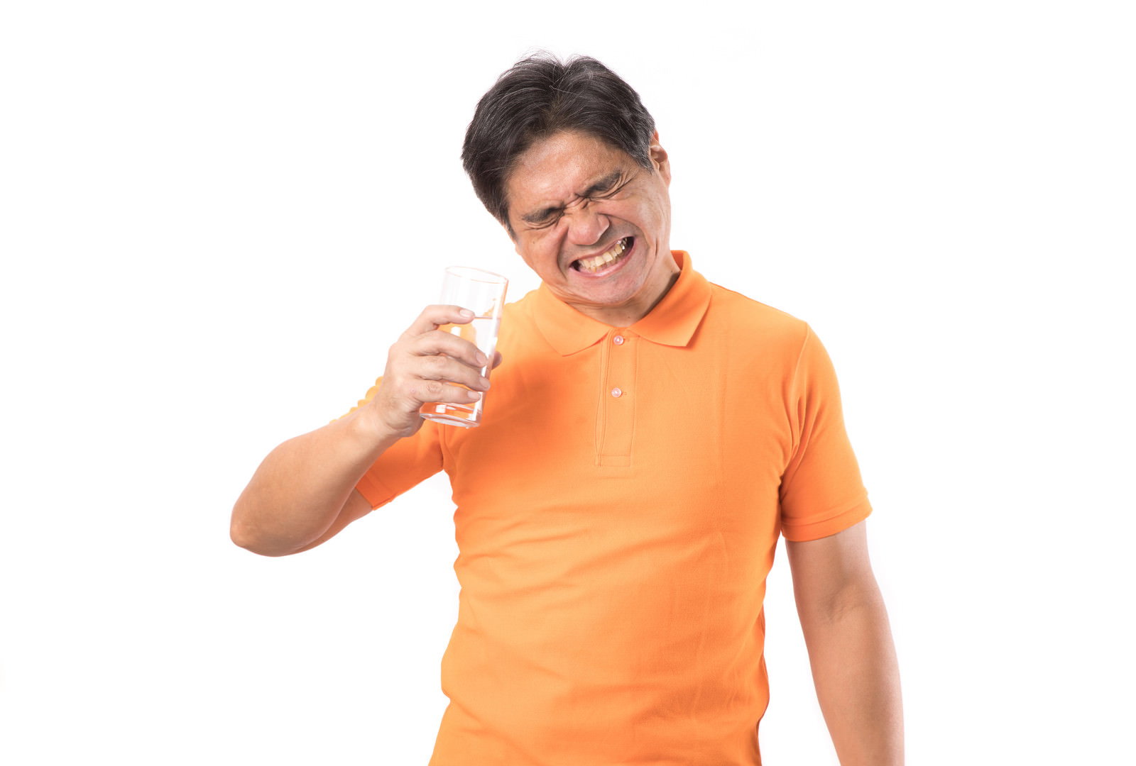 オレンジ色のTシャツを着た中年男性が水を飲んで歯がしみている表情［モデル：よたか］