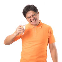 冷たい水を飲んで知覚過敏でしみる中年男性の写真