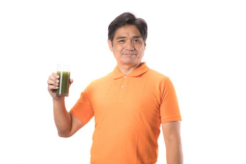 青汁を片手に持った中年男性が健康的な笑顔で栄養補給