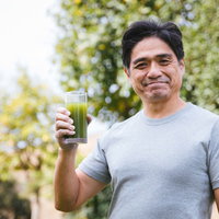屋外で健康的に青汁を飲むお父さんの写真