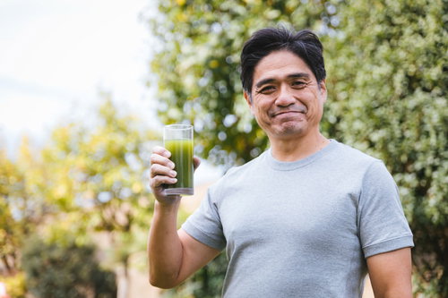 屋外で健康的に青汁を飲むお父さん