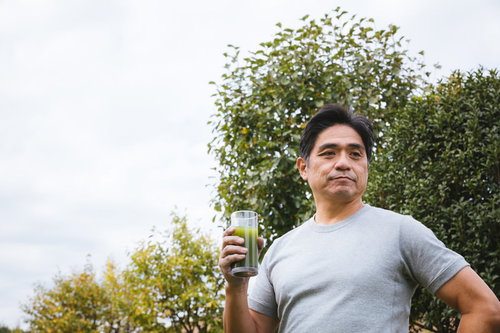 青汁を手に持つ中年男性の健康的なライフスタイル
