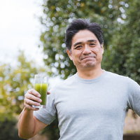 青汁を手に爽やかに笑う中年男性の健康的なライフスタイルの写真