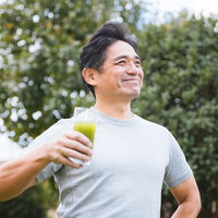 屋外で青汁を飲む中年男性の写真