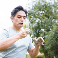 青汁の苦さに驚きを隠せない中年男性の表情の写真