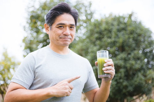 青汁を指差しながら笑顔を見せる健康志向の男性