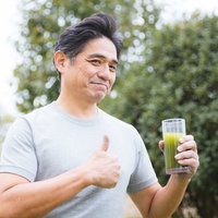 父が勧めてきた青汁に親指を立てる中年男性の写真