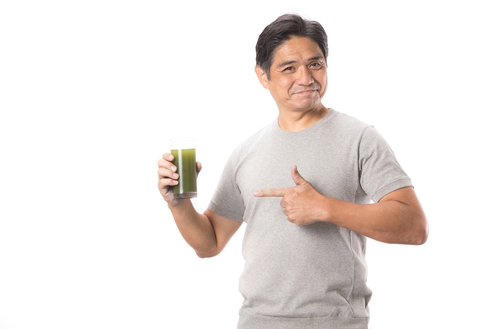青汁のグラスを持ち親指で指さしている中年男性［モデル：よたか］