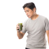 とても苦い青汁を飲んで嫌な顔をする中年男性の写真